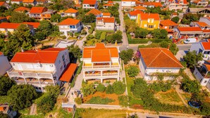 An aerial view of a residential area with houses, green spaces, and a central building with a balcony. - Apartments Mladenka- Two Bedroom Apartment with Balcony and Sea View (Orebic)