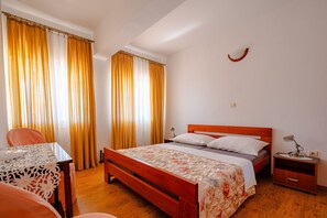 Une chambre à coucher avec un lit en bois, une table de chevet, une table et des rideaux.