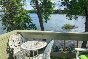 Una terraza con mesa y sillas con vista a un lago.