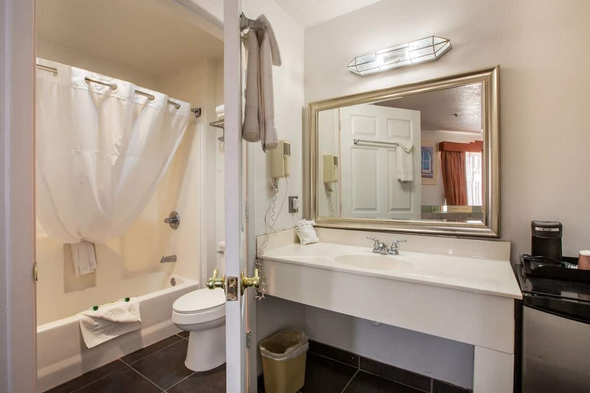 A bathroom with a bathtub, toilet, sink, and mirror.