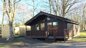 En lille træhytte med veranda og en indhegnet have.