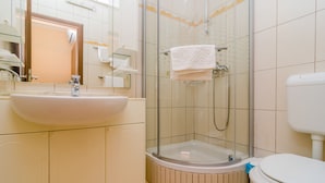 Une salle de bain équipée d’un lavabo, de toilettes et d’une douche à parois de verre.