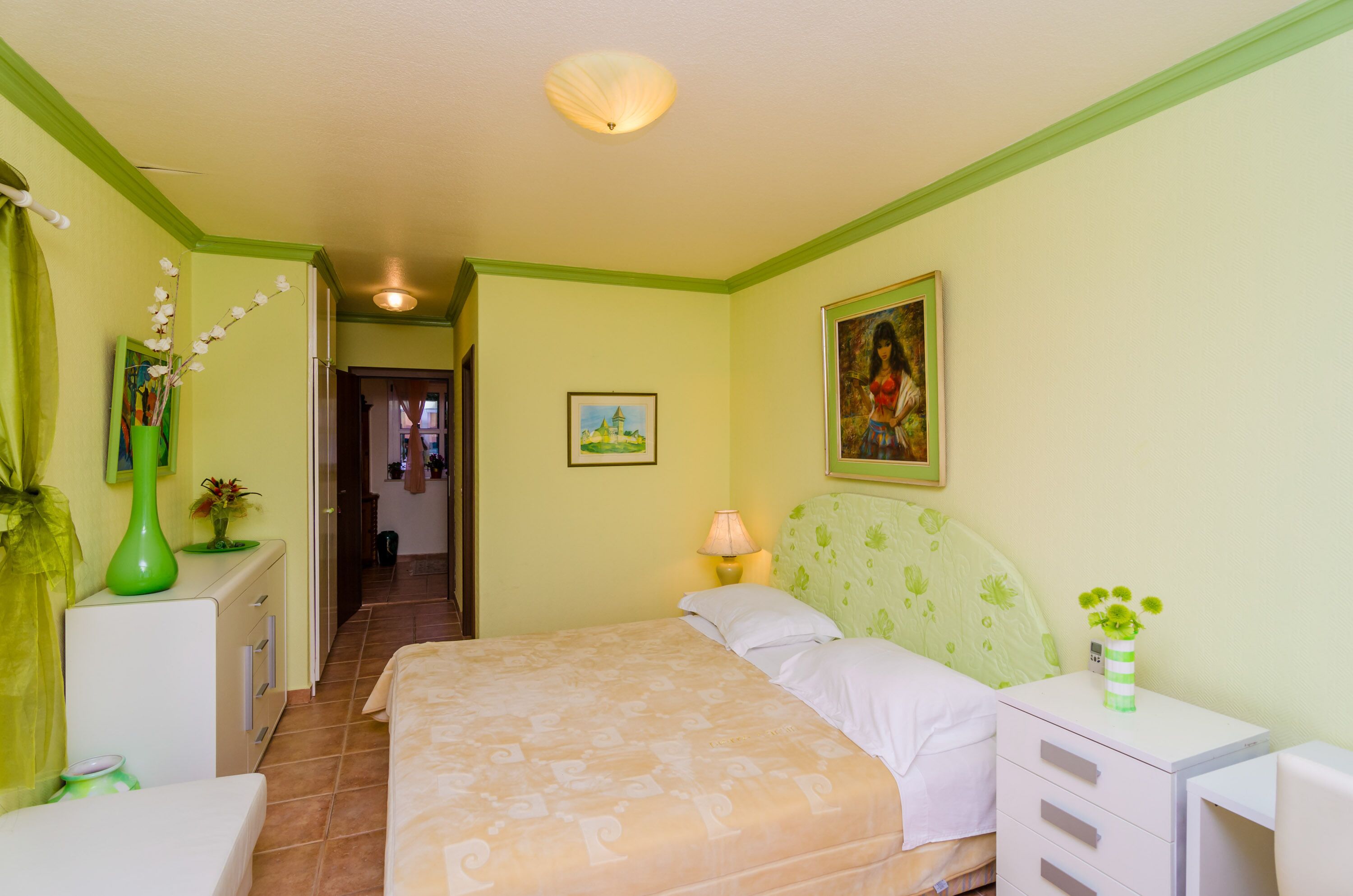 Een slaapkamer met een bed, nachtkastjes, een lamp en een schilderij aan de muur.