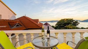 Un balcon avec une table, des chaises et une bouteille de vin.