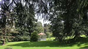 Un parc doté d’un kiosque, d’un banc et d’une pelouse bien entretenue.