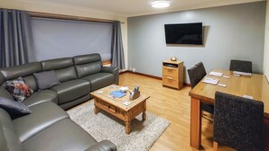 Un salon comprenant un canapé, une table basse, un téléviseur et une table à manger avec des chaises.