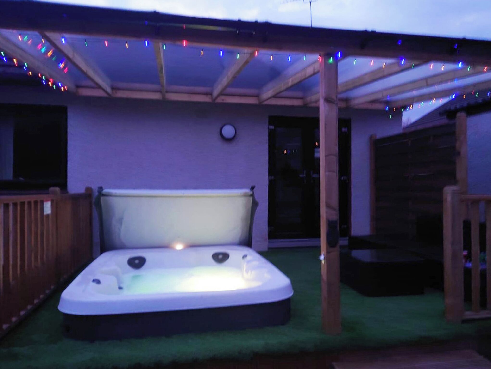A hot tub under a covered patio with string lights.
