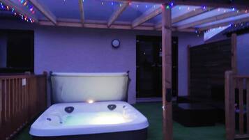 A hot tub under a covered patio with string lights.