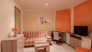 Un espacio habitable compacto con sofá, mesa de comedor, televisor y un mueble.