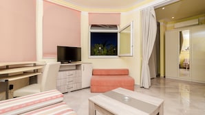Een moderne hotelkamer met een flatscreen televisie, een bureau, een comfortabele zithoek en uitzicht op de nachthemel door een raam.