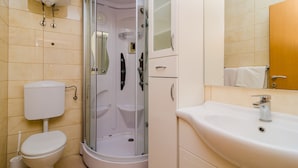 Een moderne badkamer met een douchecabine van glas, een wit toilet en een wastafel met spiegel erboven.