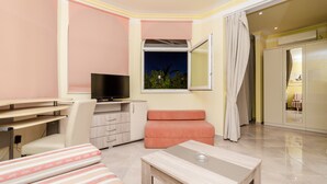 Una habitación de hotel moderna con televisión de pantalla plana, un escritorio, una zona de estar con asientos acolchados y vistas al cielo nocturno a través de una ventana.
