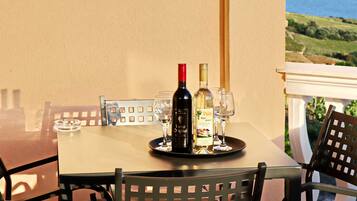 A table with a bottle of wine and glasses on a tray, overlooking a scenic view.