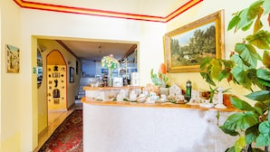A hotel lobby with a reception desk, a staircase, and a dining area.