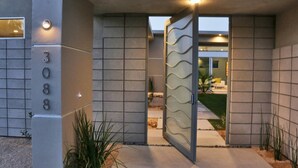 Een moderne gevel met glazen deur, een betonfacade en het nummer '308' op de muur.