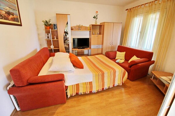 Una sala de estar acogedora con un sofá, un televisor y un mueble de madera.