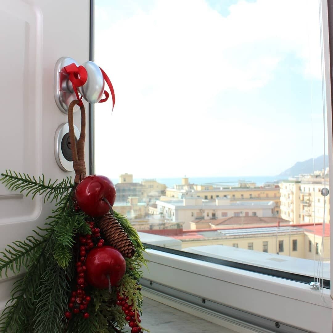 A window with a view of a cityscape and a decorative wreath on the window sill.