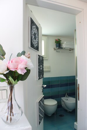 Een badkamer met toilet, bidet en een vaas met bloemen op een aanrecht.