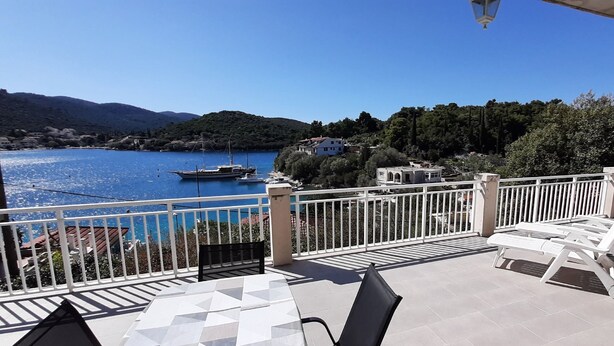 A terrace with a view of a lake, boats, and buildings in the background. - Apartment Classic Korčula - Two Bedroom Apartment with Terrace and Sea View (Korcula)