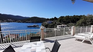 Une terrasse offrant une vue sur un lac, des bateaux et des bâtiments en arrière-plan.