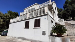 A two-story building with a balcony and a staircase leading to the upper floor. - Apartment Classic Korčula - Two Bedroom Apartment with Terrace and Sea View (Korcula)