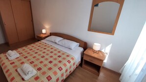 A hotel room with a bed, two bedside tables with lamps, a wardrobe, and a mirror on the wall. - Apartment Classic Korčula - Two Bedroom Apartment with Terrace and Sea View (Korcula)