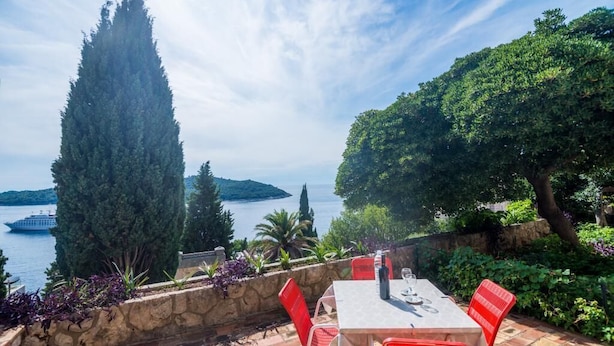 Terassi, jossa on pöytä ja tuoleja, ja josta avautuu näkymä vesistölle. Kauempana näkyy vene.