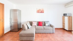 A living room with a grey sofa, a small table, a microwave, and a refrigerator. - Apartment Budimir - Two Bedroom Apartment with Balcony (Podstrana)