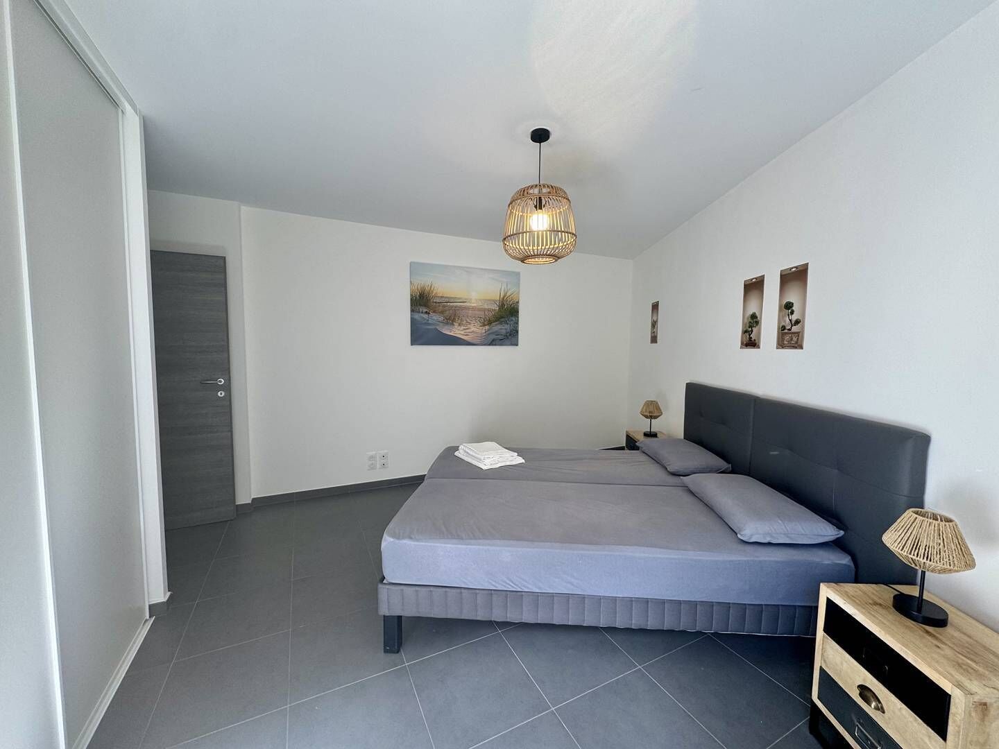Ein modernes Schlafzimmer mit einem Bett, einer Nachttischlampe und einem Bild an der Wand.