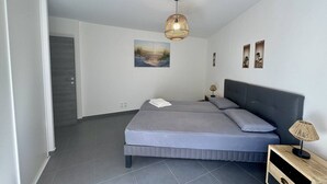 A modern bedroom with a bed, a bedside lamp, and a painting on the wall. - Fronte di Mare 2 bedroom town center sea view (PROPRIANO)