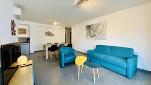 A modern living room with a blue sofa, a yellow coffee table, and a flat-screen TV. - Fronte di Mare 2 bedroom town center sea view (PROPRIANO)
