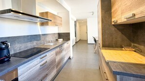 A modern kitchen with a stainless steel range hood, wooden cabinets, and a black kettle on the counter. - Fronte di Mare 2 bedroom town center sea view (PROPRIANO)