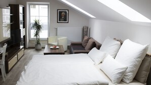 Ein modernes Schlafzimmer mit einem großen Bett, einem Schreibtisch, einem Sessel, einem Fernseher und einer Topfpflanze.