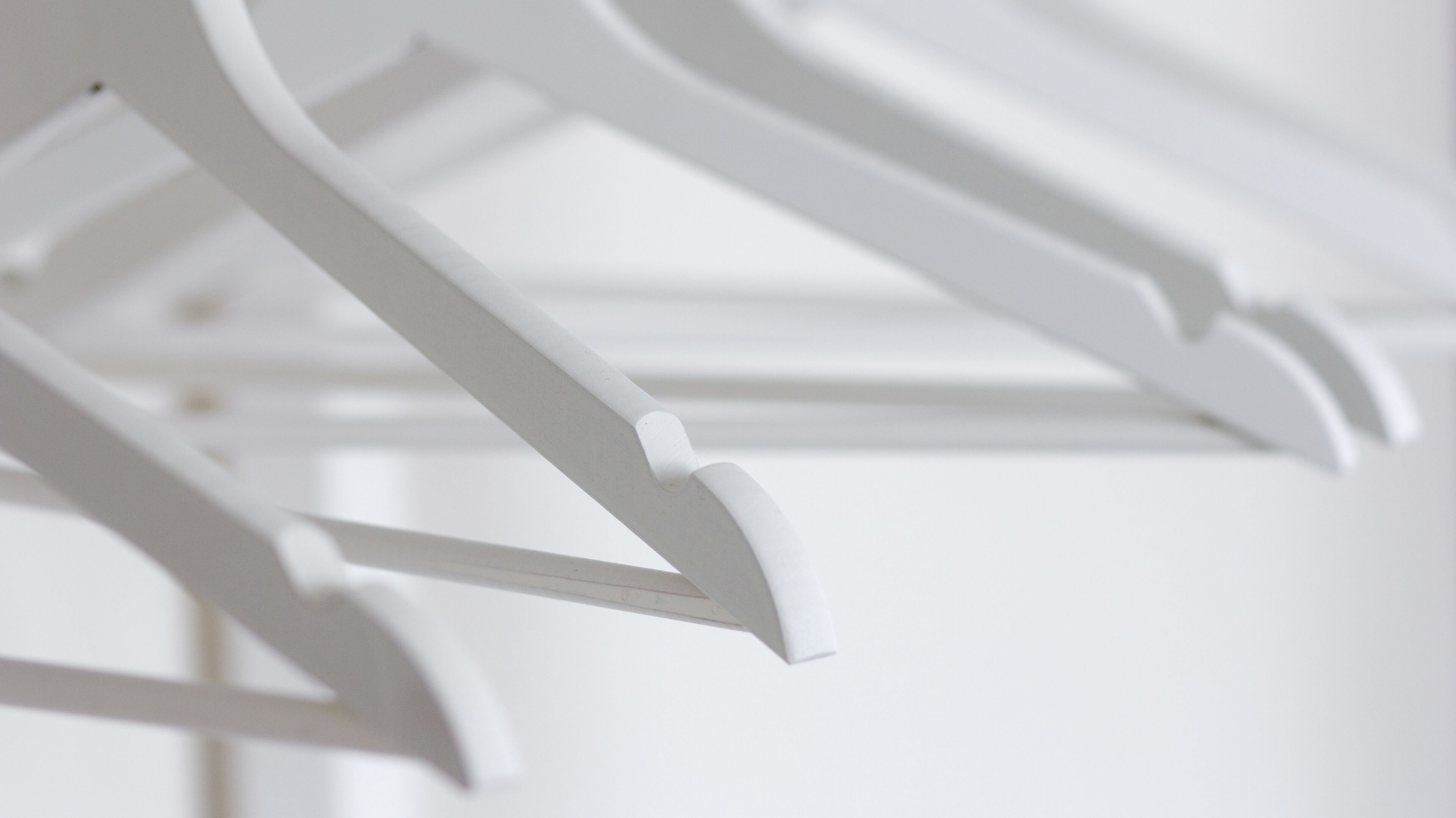 A close-up of a white metal chair with a curved backrest.