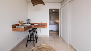 Cocina compacta con encimera de madera, dos taburetes negros y una lámpara colgante.