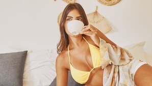 Una persona sentada en una cama con un frasco de Nutella, una manzana y una taza.
