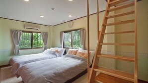 Una habitació amb dos llits, una escala de fusta i una finestra amb cortines.