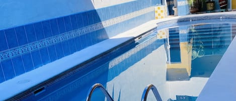 Ein Schwimmbecken mit gefliestem Beckenrand und Metallhandläufen.