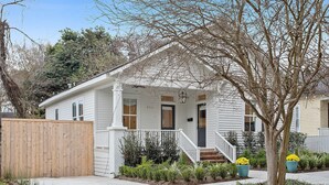 A two-story house with a front porch, a wooden fence, and a tree. - Luxury Cottage in Historic Beauregard Town  (Baton Rouge)