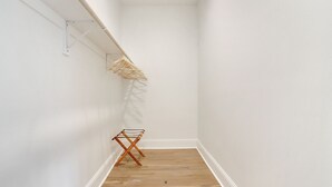 A narrow hallway with a wooden floor, a clothes drying rack on the wall, and a small wooden stool. - Luxury Cottage in Historic Beauregard Town  (Baton Rouge)