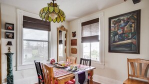 Un comedor con una mesa de madera, sillas, una araña y obras de arte en las paredes.