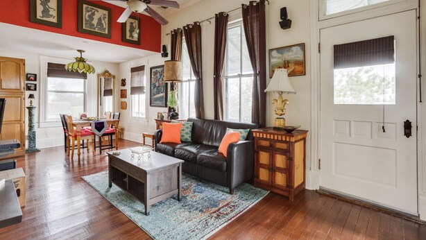Amplia sala de estar con un sofá de cuero negro, una mesa de centro y un comedor con muebles de madera.