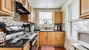 Una cocina con armarios de madera, una estufa y un ventanal con persianas.