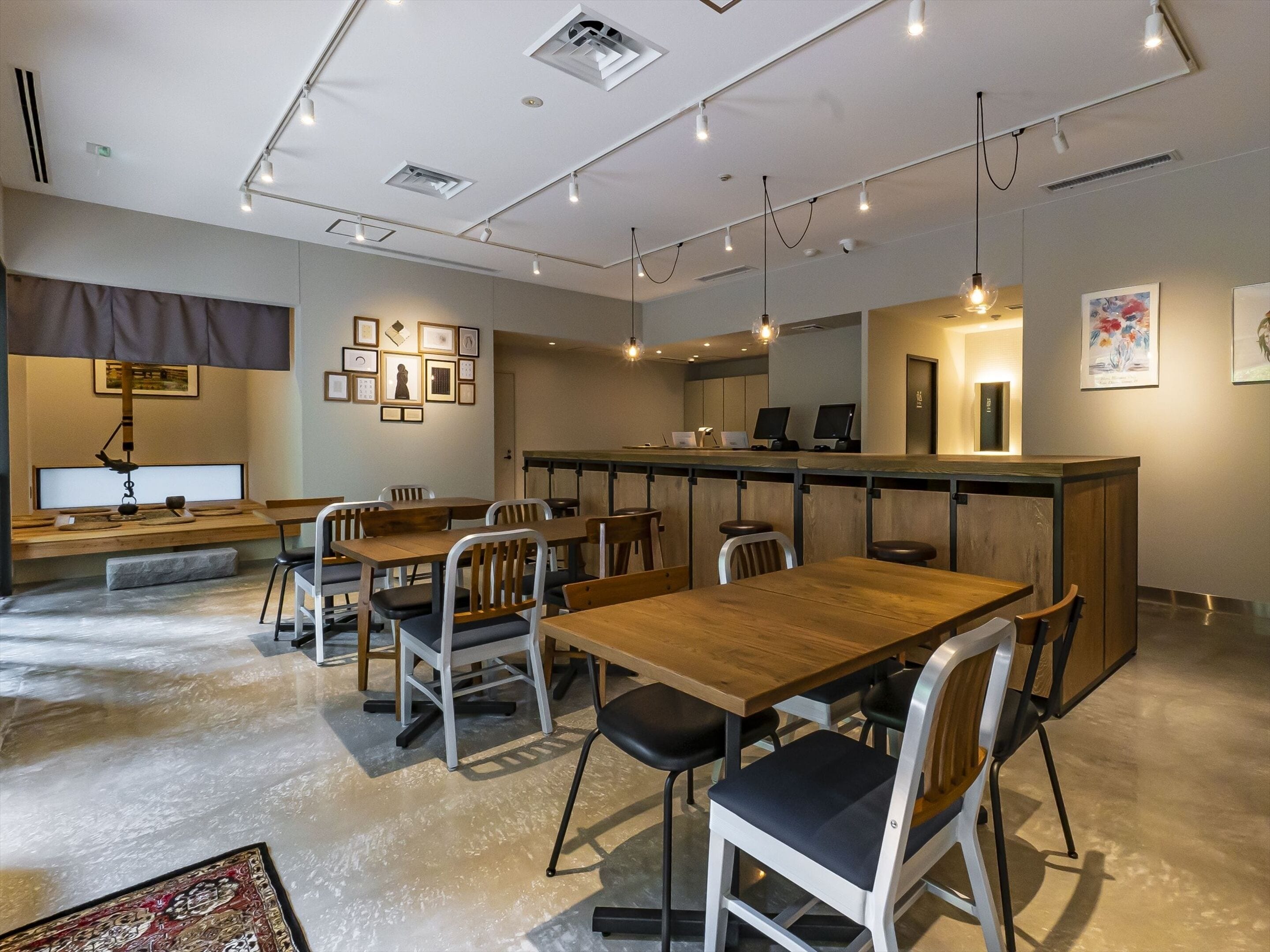 Un comedor moderno con mesas y sillas de madera, una barra y cuadros en las paredes.