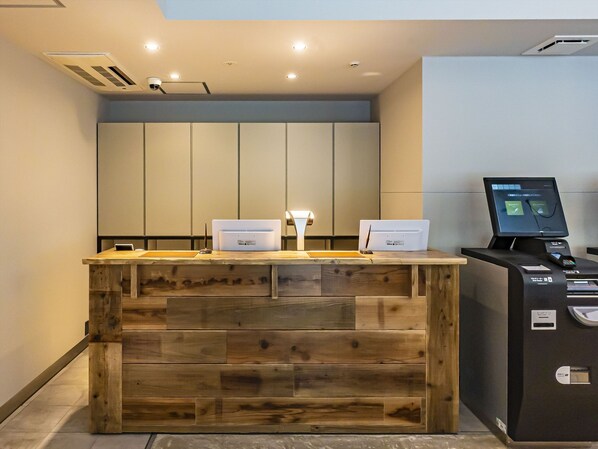 A reception desk with a wooden finish, a digital kiosk, and a ceiling with recessed lighting. - Bay Hotel Tokyo Hamamatsucho (Tokyo)