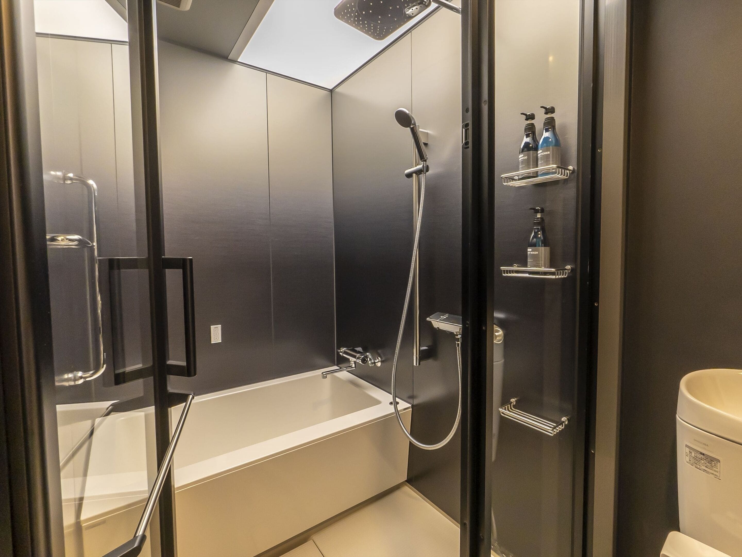 A modern bathroom with a glass-enclosed shower, a white bathtub, and a toilet.