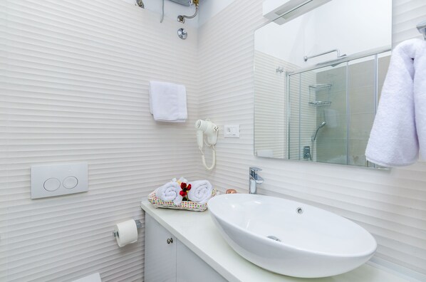 Une salle de bain moderne avec un lavabo blanc, une cabine de douche en verre et un porte-serviettes.