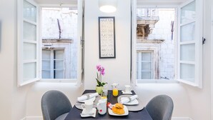 A dining area with a table set for breakfast, including plates, cups, and a jug of orange juice.