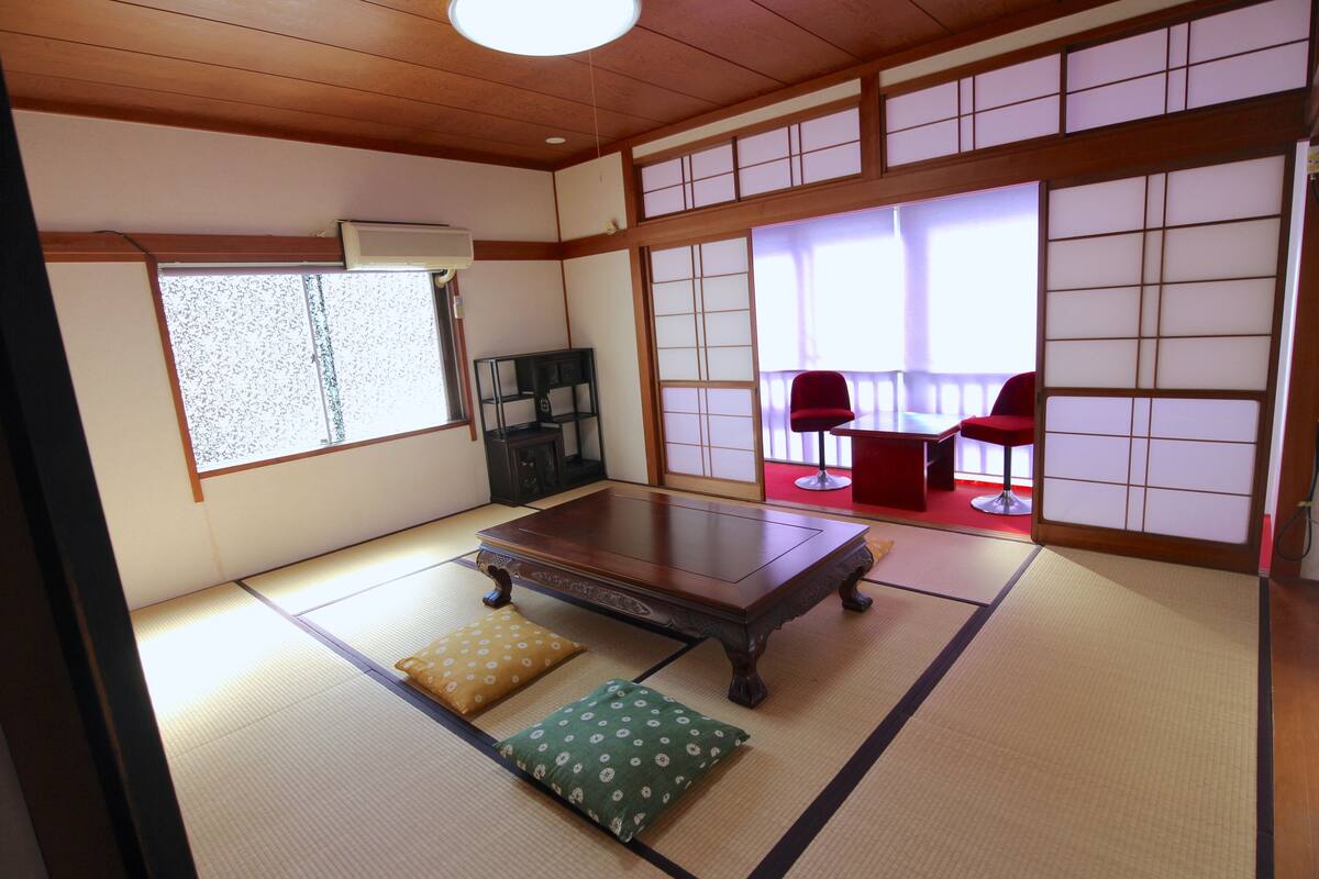 A traditional Japanese room with tatami flooring, a low wooden table, and shoji screens.