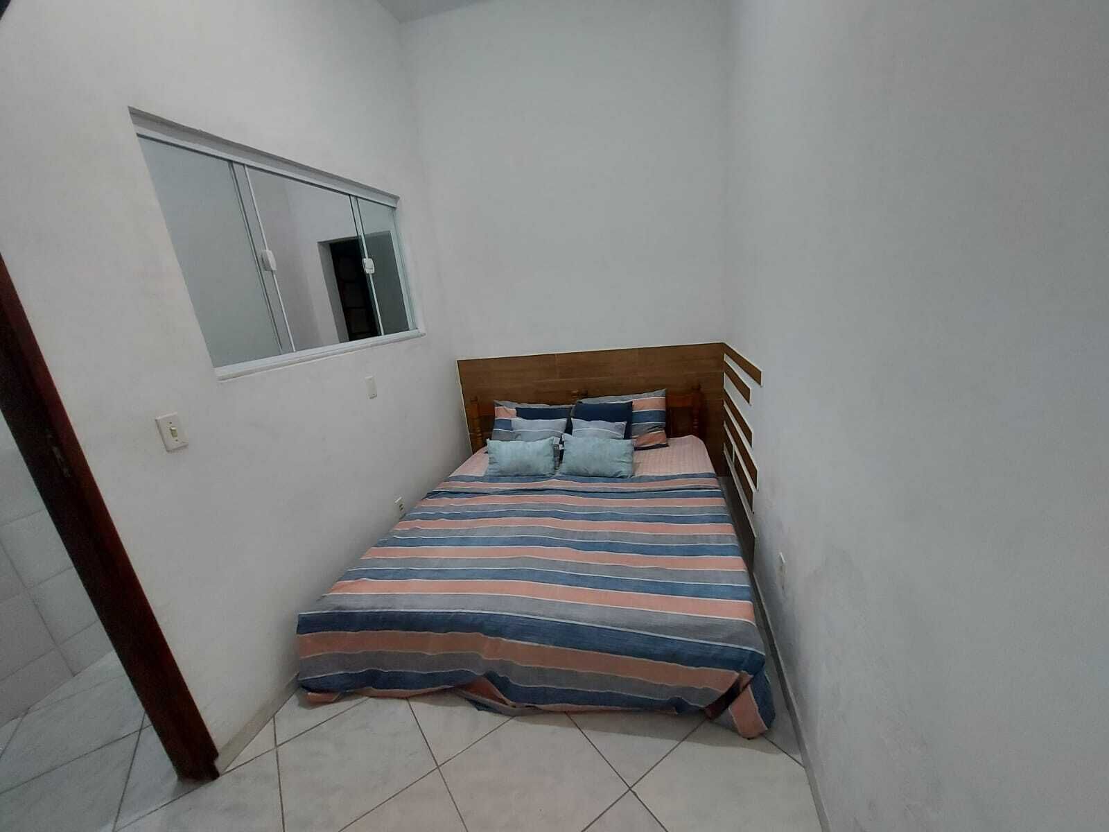 Um quarto pequeno e estreito com uma cama de solteiro, uma janela e uma porta.